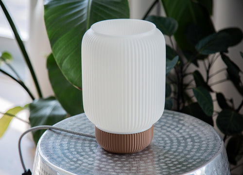 Close-up of a ribbed translucent plastic shade with warm yellow light glowing through the center.