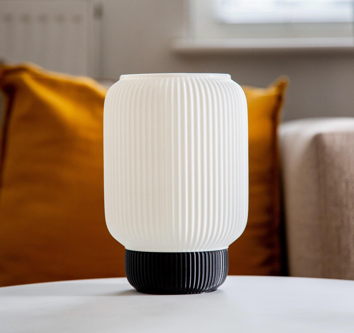 A ribbed translucent white Plasticlampshade with a black fluted base, displayed on a white surface against a neutral gray background.