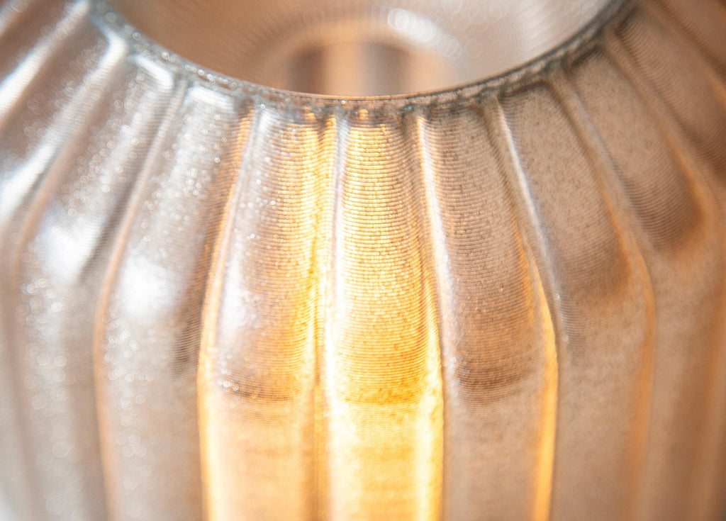 Close-up of a ribbed translucent 3D Printed shade with warm yellow light glowing through the center.