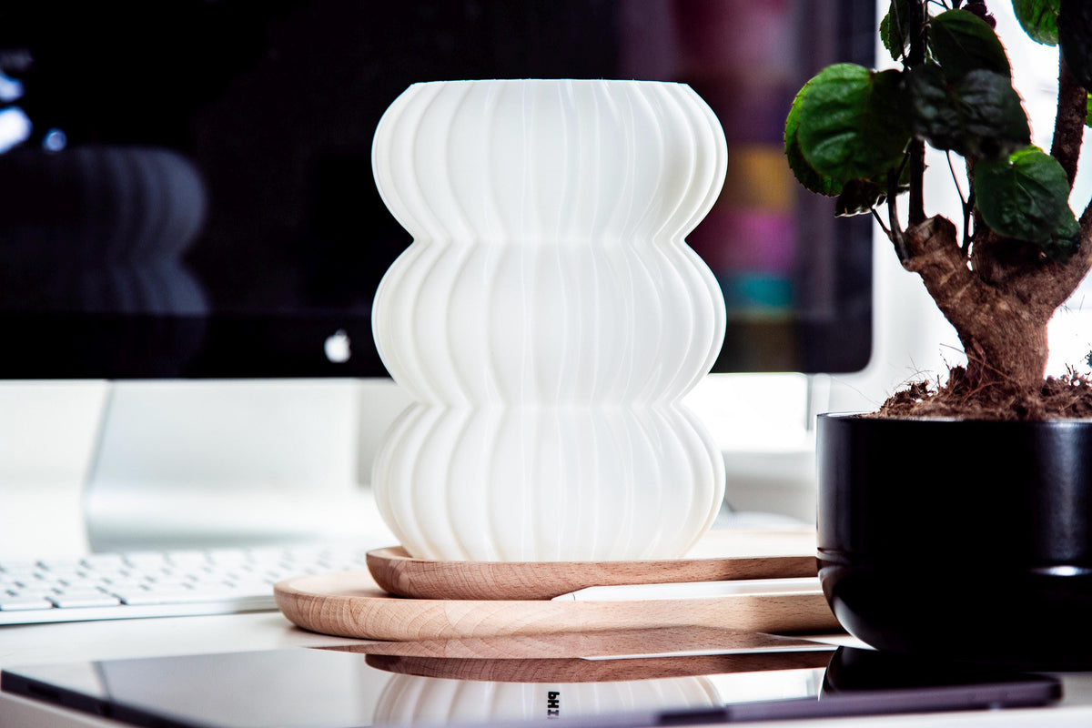 Close-up of a ribbed translucent plastic shade or vase with warm yellow light glowing through the center.