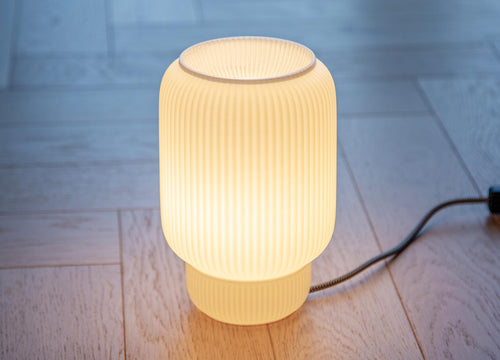 a modern bubble cluster table lamps on a light wood floor, one glowing with a warm white light  with a metal cord visible on the right.